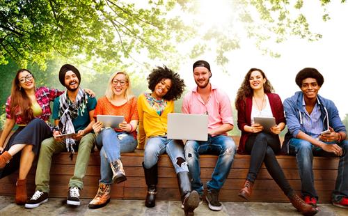 A diverse group of adults sitting on a bench outside.  